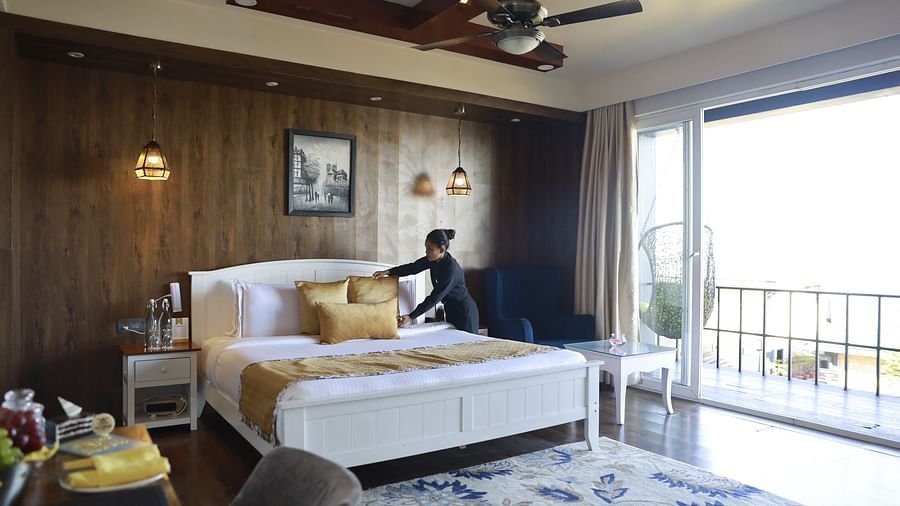a person making the bed in the Rain Forest Suite - Polo Orchid Resort, Cherrapunji