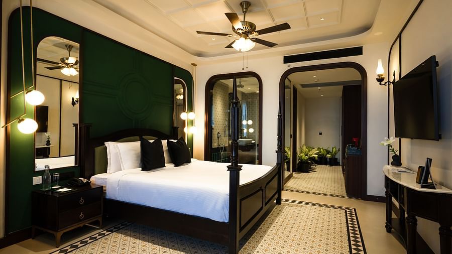 An image of a bedroom with king size bed, flat TV screen, and bedside table with lamp - Polo Orchid Resort, Cherrapunjee