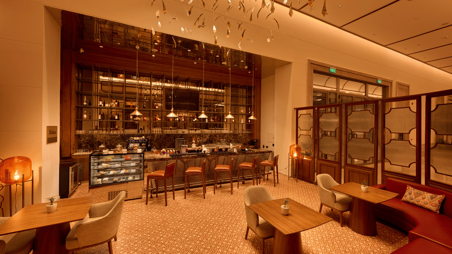Mahua Bar space at Prachi Sarovar Premiere, Bhubaneswar, showing wooden tables, chairs, a service counter, and decorative glass panels.