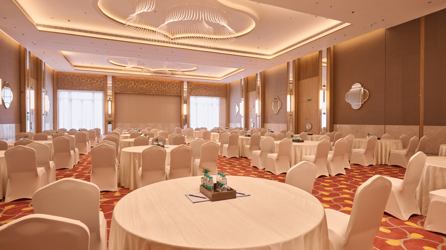 Event space at Prachi Sarovar Premiere, Bhubaneswar, showing a close-up view of a round table with chairs in a large hall with patterned flooring.