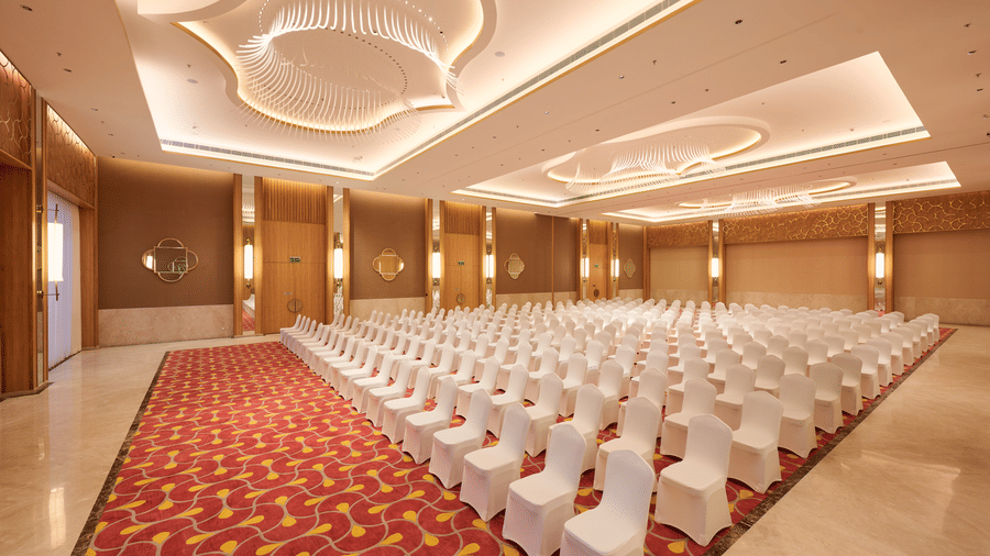 Large event hall at Prachi Sarovar Premiere, Bhubaneswar, featuring rows of chairs set up on a patterned carpet under modern ceiling lights.