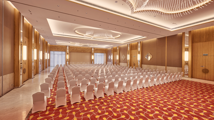 Spacious hall at Prachi Sarovar Premiere, Bhubaneswar, with theatre-style seating arrangements, patterned carpet, and integrated lighting.