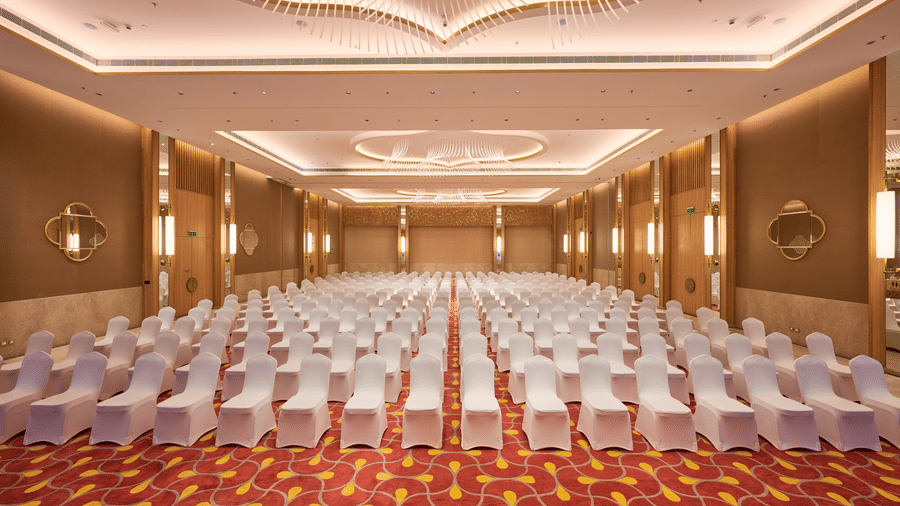 Conference hall setup at Prachi Sarovar Premiere, Bhubaneswar, with rows of seating facing forward, patterned carpet, and paneled walls.