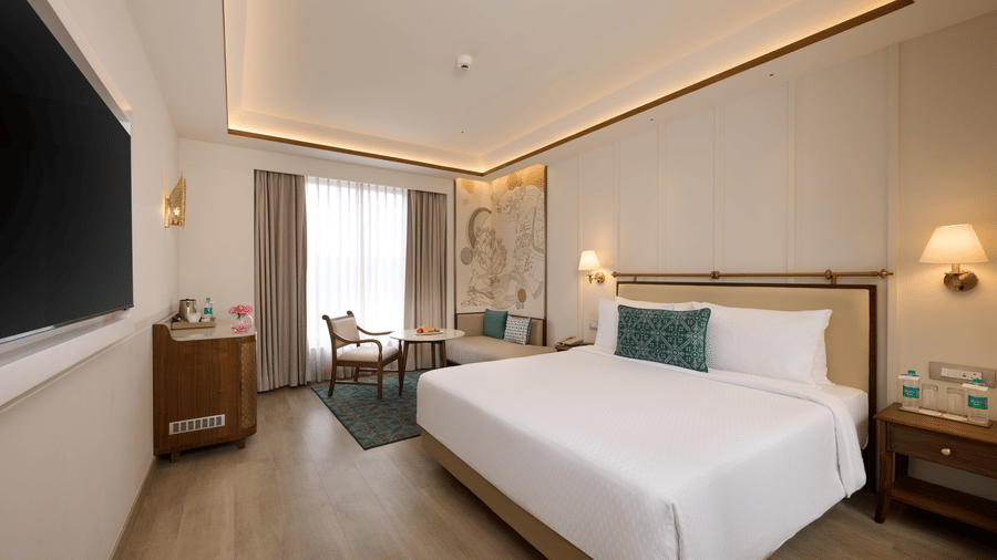 Deluxe King Room at Prachi Sarovar Premiere, Bhubaneswar, with a large bed, a wall television, a storage cabinet, and a window setup.