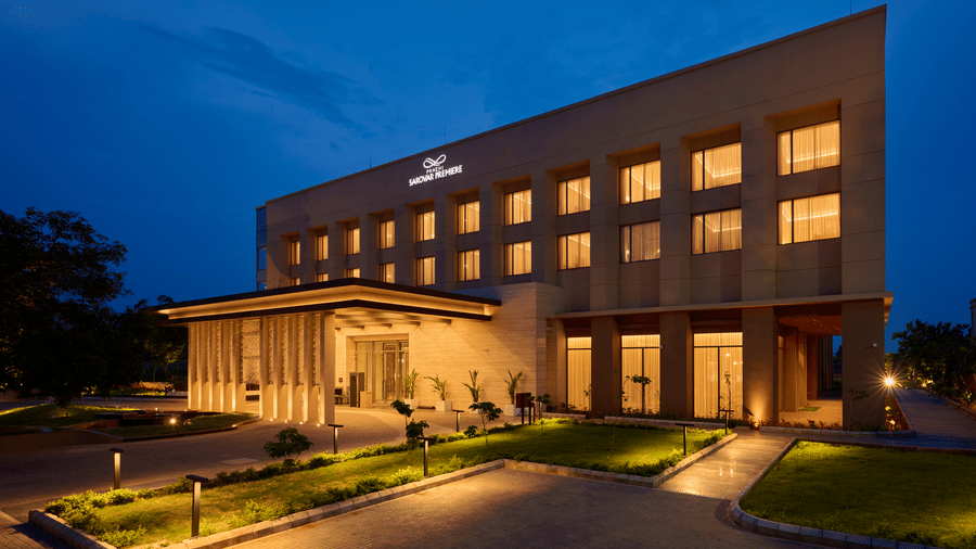 Hotel exterior of Prachi Sarovar Premiere, Bhubaneswar, at night, displaying illuminated windows, a lit entrance canopy, and a driveway.