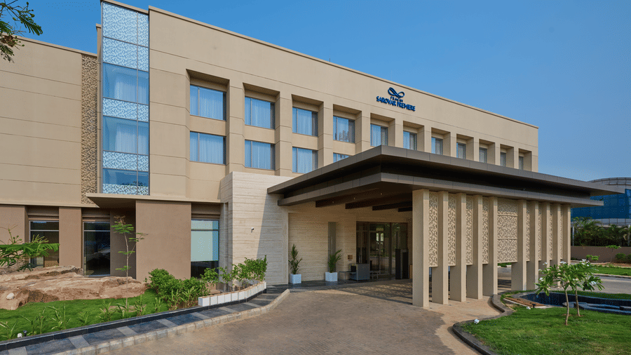 Main entrance of Prachi Sarovar Premiere, Bhubaneswar, featuring a large covered drop-off porch, concrete pillars, and a clear daytime sky.