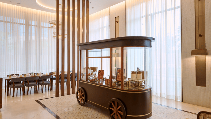 Flavours dining interior at Prachi Sarovar Premiere, Bhubaneswar, featuring a vintage-style food cart on wheels, dining tables, and large windows.