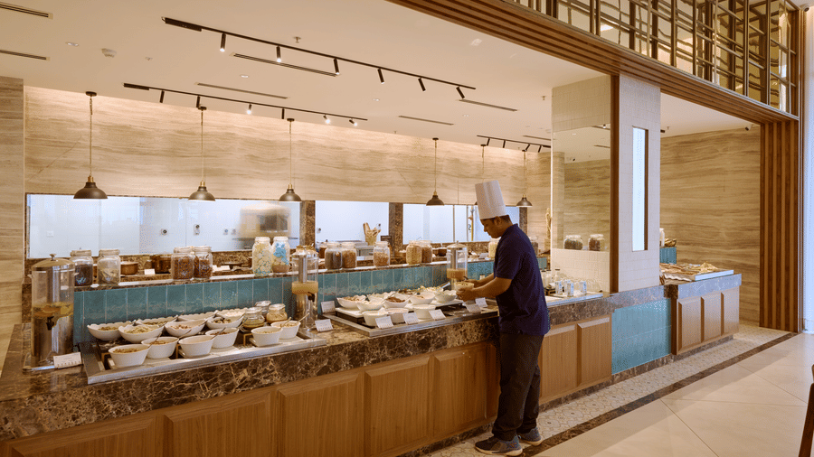 Food station at Prachi Sarovar Premiere, Bhubaneswar, featuring a stone counter with serving dishes and overhead track lighting.