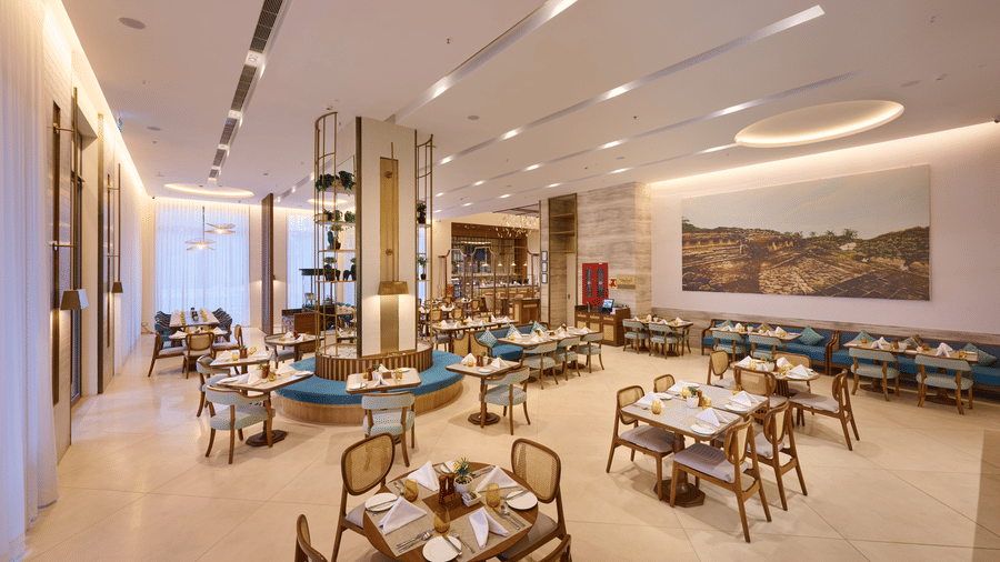 Flavours dining room at Prachi Sarovar Premiere, Bhubaneswar, arranged with multiple dining tables and chairs under a bright, recessed ceiling.