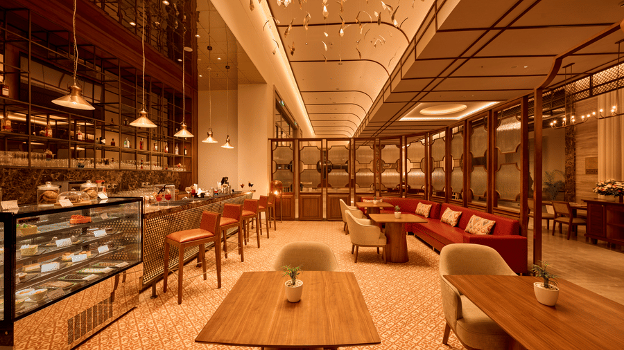 Mahua Bar at Prachi Sarovar Premiere, Bhubaneswar, featuring tables, chairs, a pastry display case, bar seating, and warm ceiling lighting.