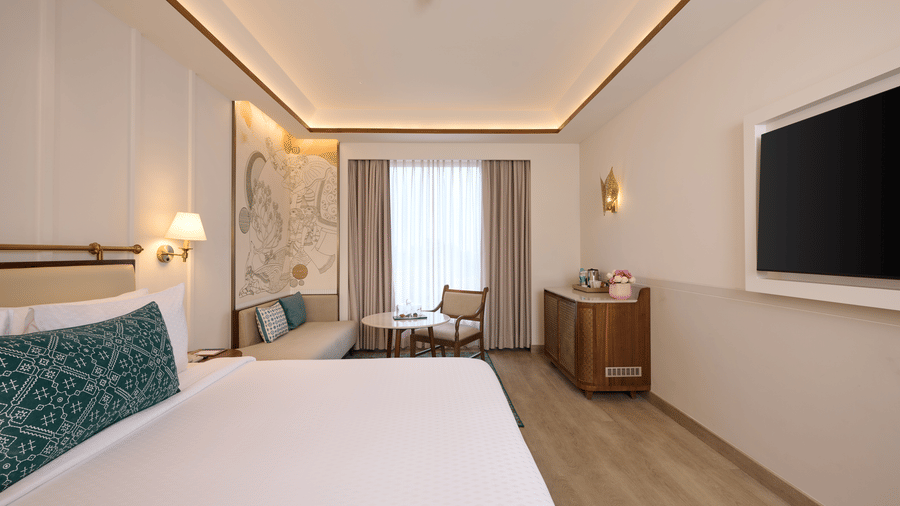 Standard Room at Prachi Sarovar Premiere, Bhubaneswar, with a large bed, a wall-mounted television, a wooden cabinet, and a window with curtains.