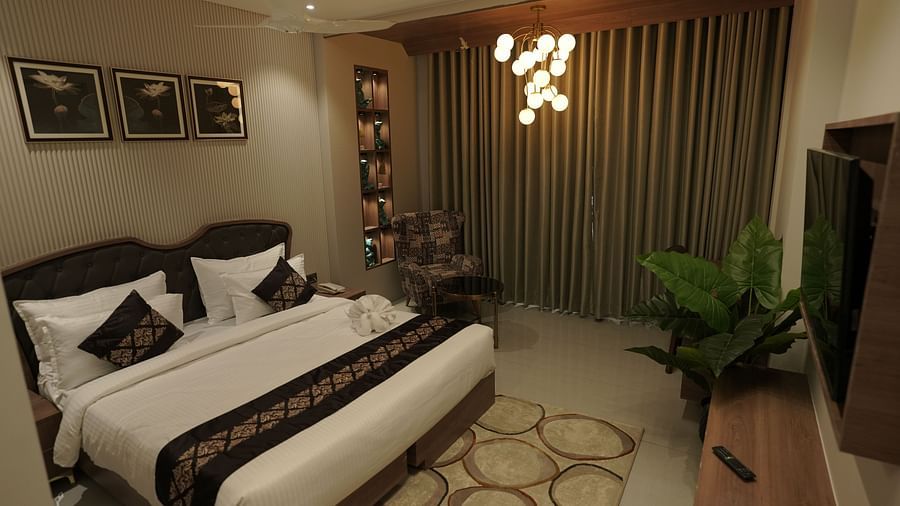 Suite Room at Pride Comfort, Dwarka with a double bed, a television and a chandelier