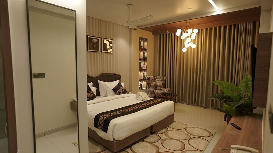 Suite Room at Pride Comfort, Dwarka with a double bed, a television and a chandelier