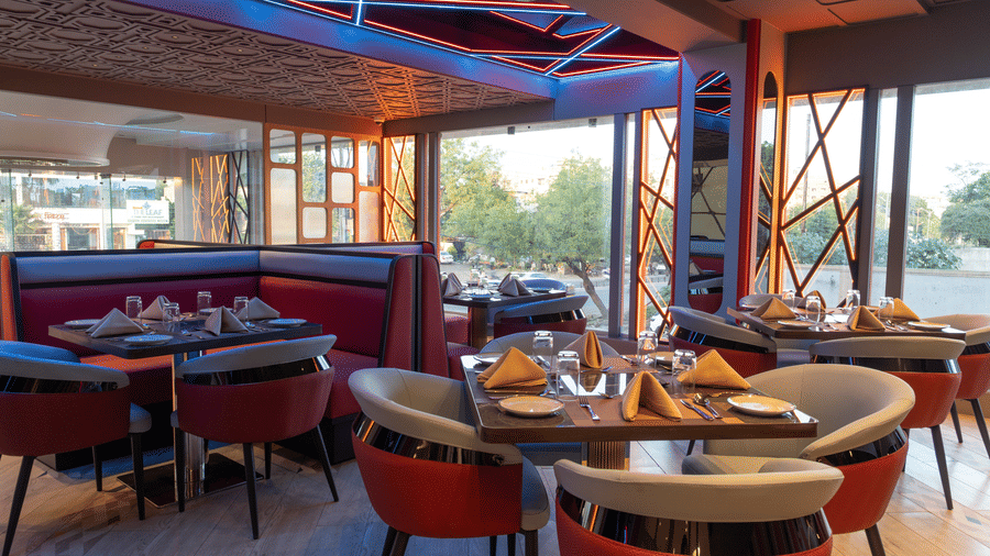 A restaurant interior featuring booth seating and individual tables with chairs, set under wooden ceiling beams | Pride Elite Chhatrapati Sambhajinagar