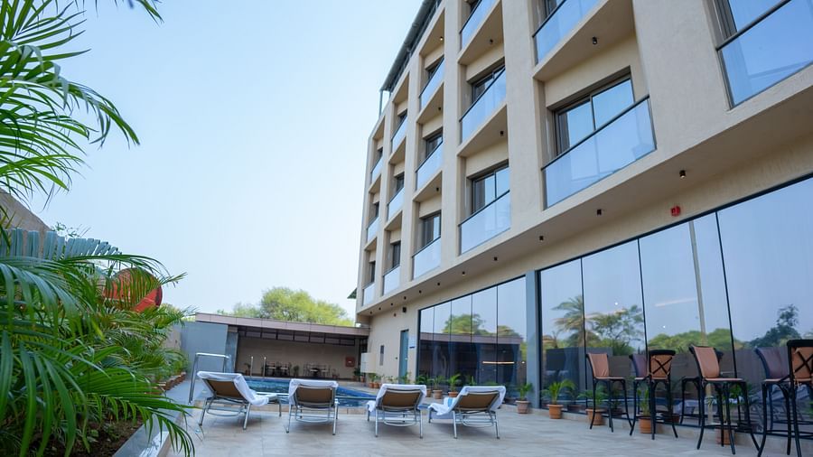 Facade of Pride Elite Daman with a pool and lounge chairs.