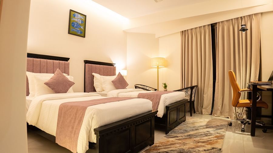 A room with twin beds and a desk with chair at Pride Elite Daman.