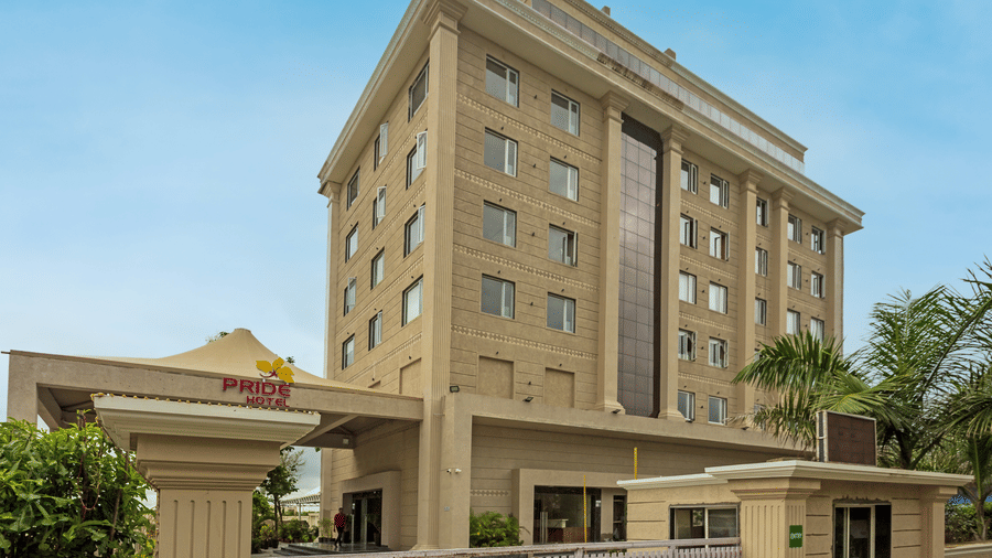 An image of Pride Hotel Bhopal Facade featuring a multi storey building surrounded by trees
