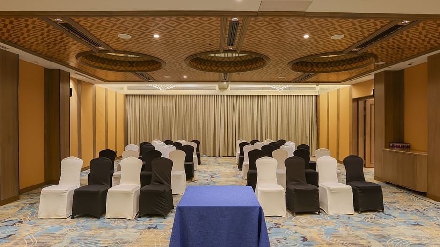 A room with rows of chairs facing a table, possibly set up for a meeting or event - Pride Hotel Pune