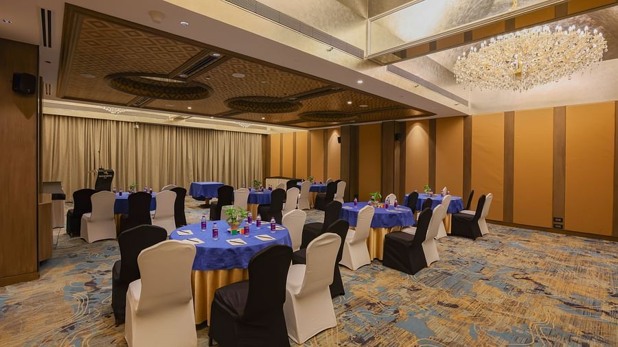 A room with rows of chairs facing a table, possibly set up for a meeting or event - Pride Hotel Pune