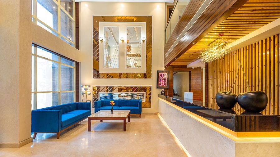 Lobby area of Pride Hotel Rishikesh featuring a reception desk in front of a sitting space arranged against large windows