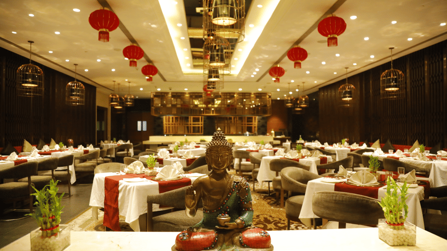 A dining space at Pride Plaza Hotel, New Delhi, with several chairs and tables arranged for dining.