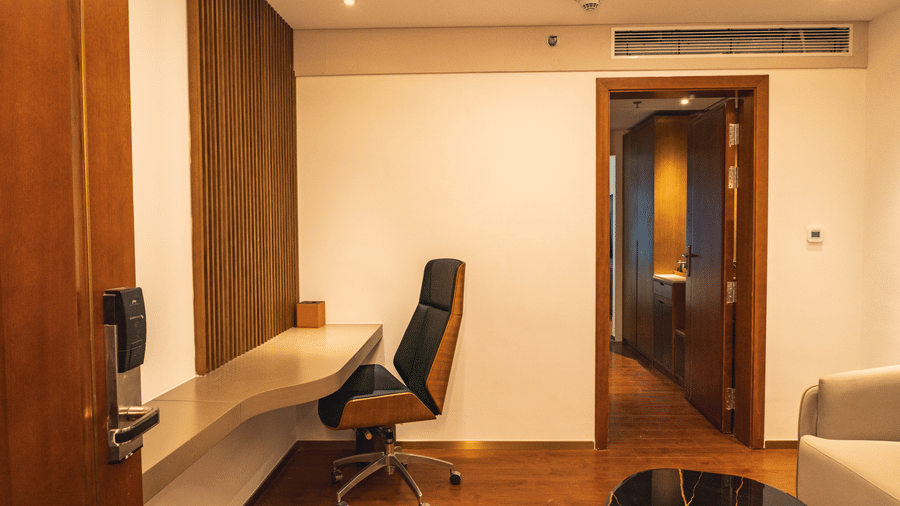 A sleek study desk, an ergonomic office chair, and a wooden doorway at Pride Plaza Indore.