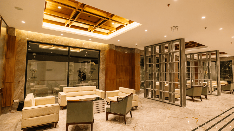 Lounge area with modern seating, warm lighting, and decorative partitions | Pride Premier Alwar
