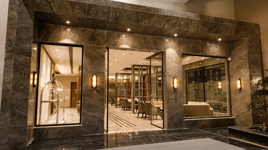 Pride Premier Alwar- Entrance to a modern building with large glass panes and sleek architectural lines.