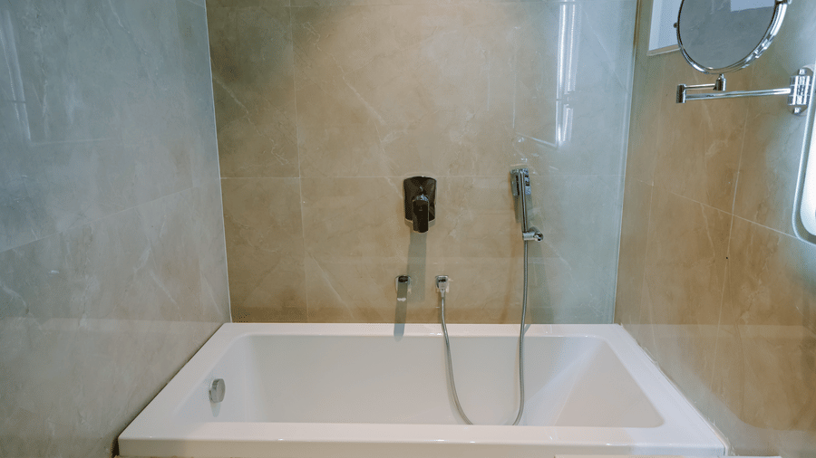 Pride Premier Alwar | A bathroom with a bathtub and a floating showerhead.