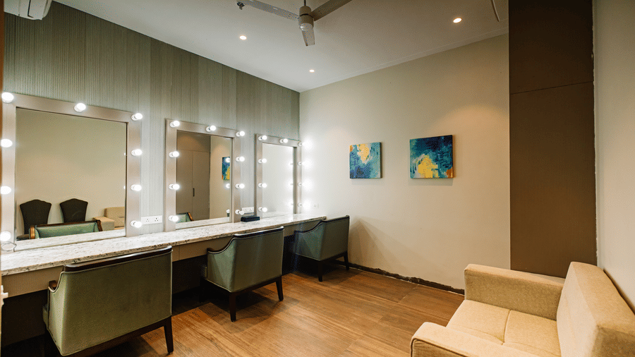 Pride Premier Alwar | a room with mirrors, a sofa, chairs, and wall-mounted frames.