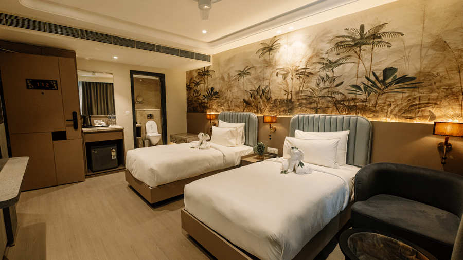 Pride Premier Alwar | A room with twin beds, bedspreads, pillows, wardobe, and a stand.