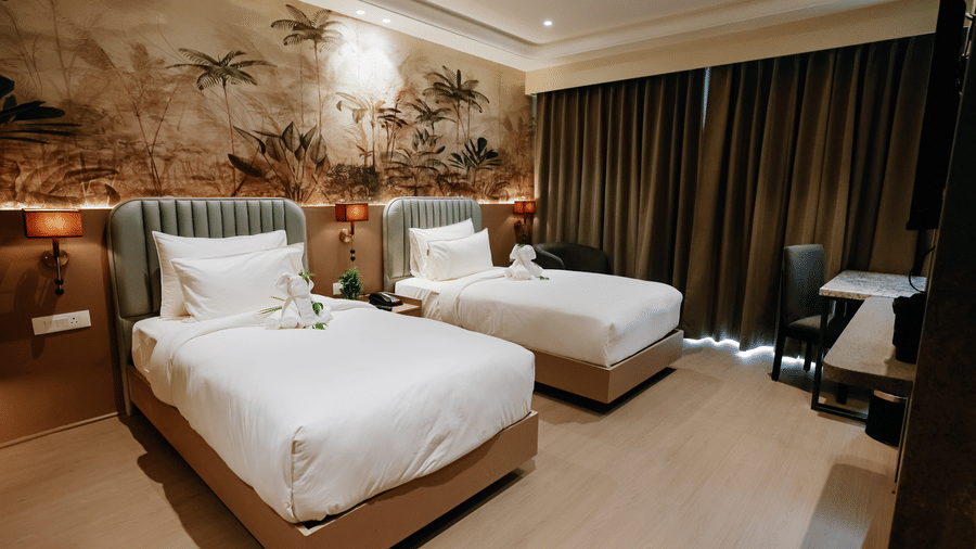 Pride Premier Alwar | A room with twin beds, bedspreads, pillows, wardobe, and a stand.