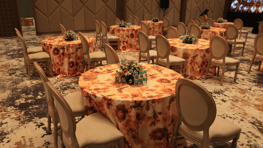 Hall set up with round tables, patterned linens, and formal chairs for an event | Pride Premier Alwar