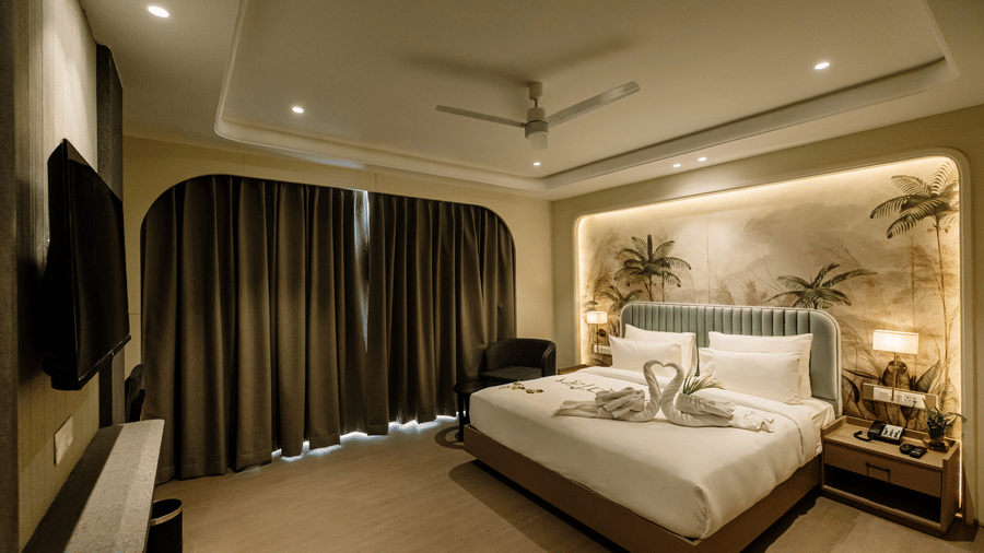 Pride Premier Alwar | A room with a large bed, spreads, pillows, and windows covered with curtains.