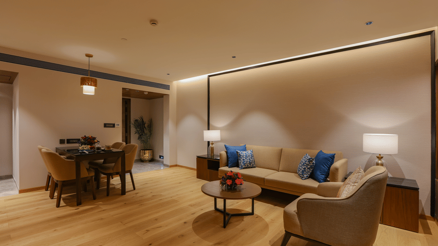A hotel room with a seating area, warm lighting, and modern design - Pride Premier Pune