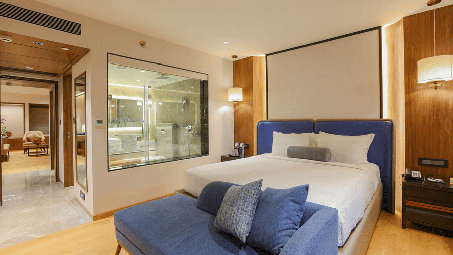 A hotel room with a bed, a couch, and a view of the outside - Pride Premier Pune