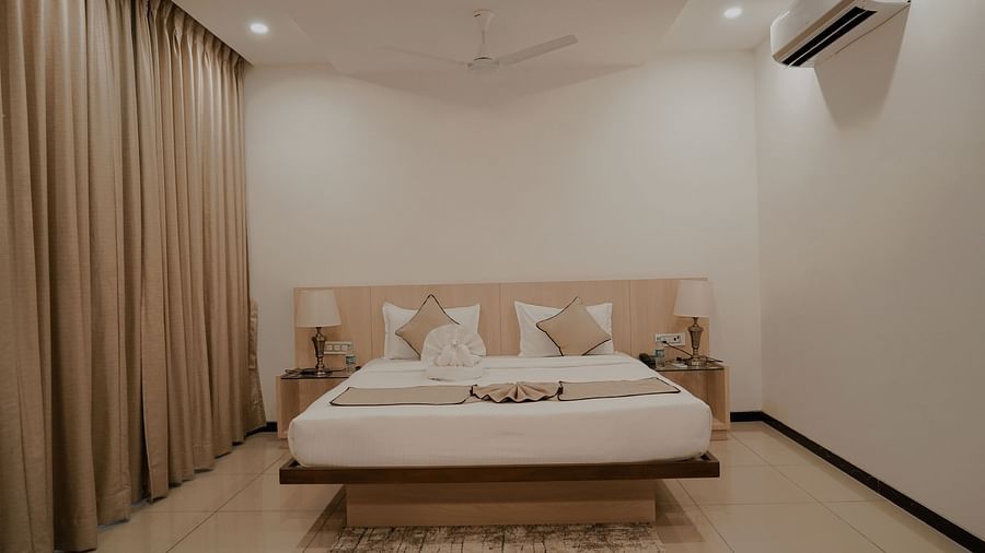 Pride Ranakpur Resort Convention Centre - interior view of the deluxe room featuring an air conditioner a fan and a queen size bed