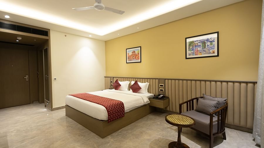 A cosy hotel room at Pride Resort, Jodhpur, with a double bed, bedside tables, and framed artwork on the wall.