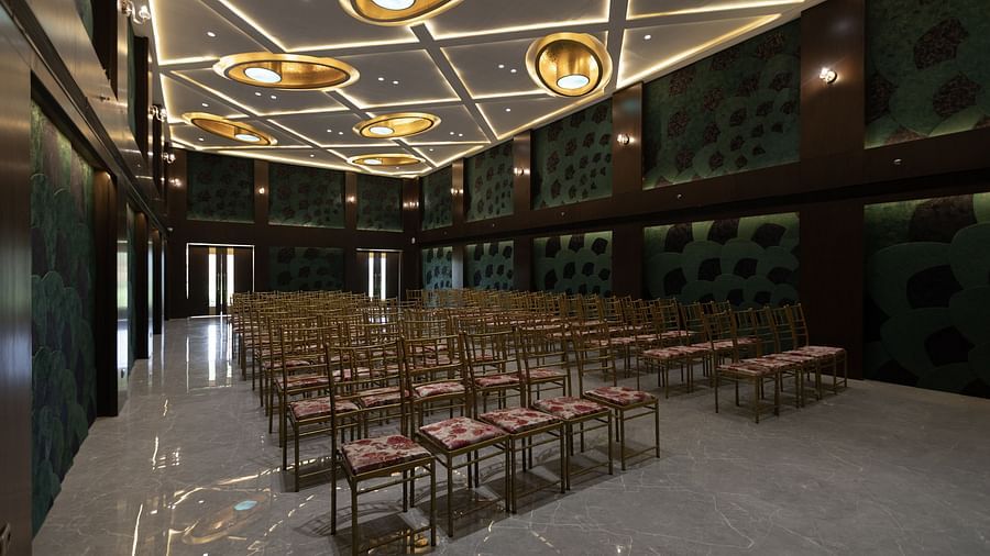 A stylish conference hall at Pride Resort, Jodhpur, featuring rows of chairs, patterned walls, and decorative ceiling lights.