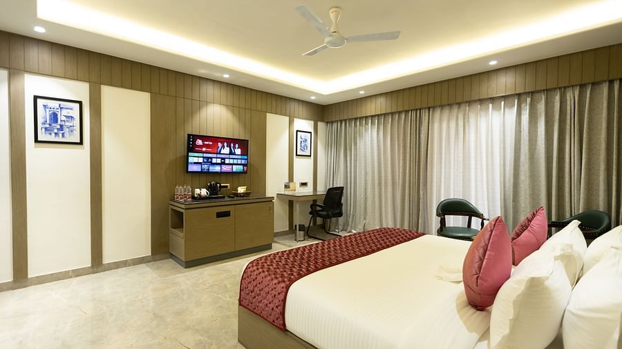 A well-appointed hotel room at Pride Resort, Jodhpur, featuring a large bed, TV, and seating area under warm lighting.
