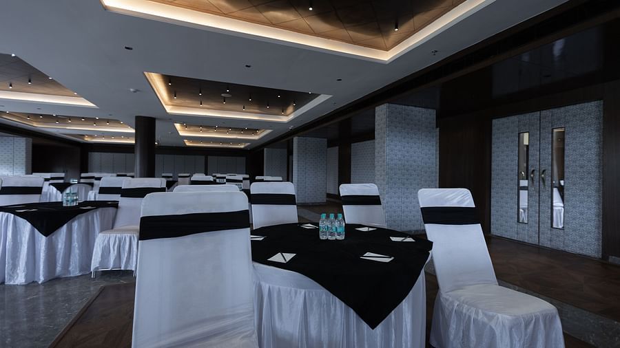 A banquet hall at Pride Resort, Jodhpur, with round tables and chairs dressed in white covers and black sashes.