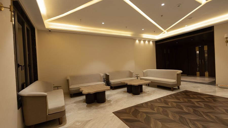 A modern lounge area with sofas and coffee tables under geometric ceiling lights at Pride Resort, Jodhpur.