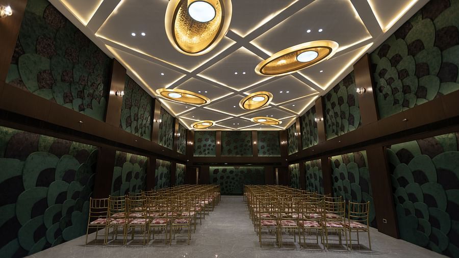 A stylish conference hall at Pride Resort, Jodhpur, with rows of chairs and an artistic ceiling featuring circular lights.