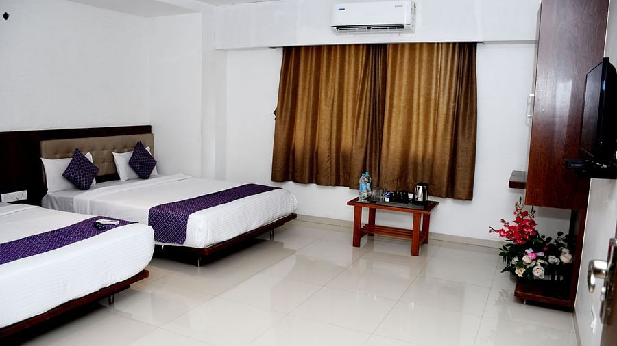 Presidential Family Suite at Pushpak Resort, Shirdi, featuring two cozy beds, a corner wardrobe, and a table