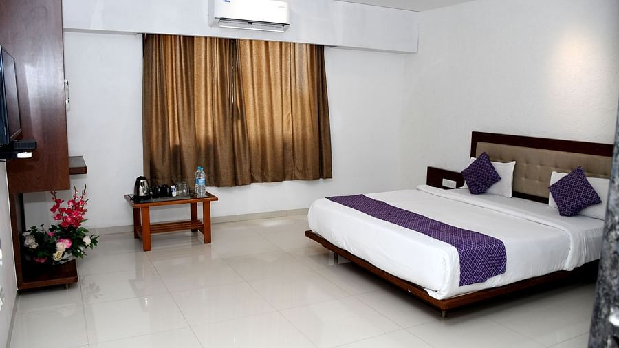 Presidential Family Suite at Pushpak Resort, Shirdi, featuring a cozy bed, a corner cupboard, and a table