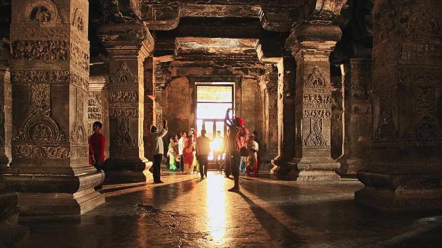 an image taken from inside a Temple with the entrance in the background and people walking from it