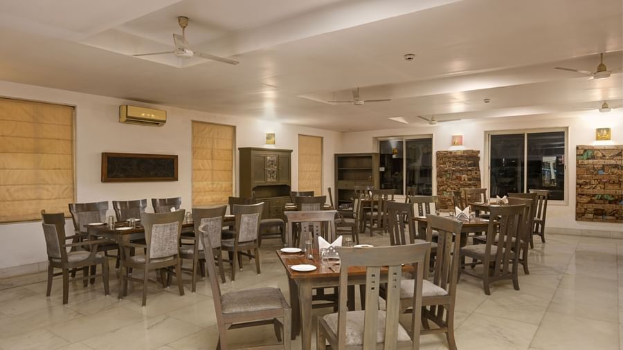 Interior dining hall at Ram Pratap Palace in Udaipur, with multiple wooden tables and chairs set up for guests, featuring modern decor and ambient lighting.