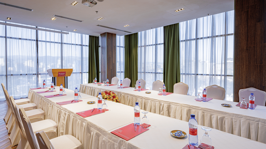 An overview of a meeting room with a parallel table set-up with water bottles and chairs in view at Ramada by Wyndham Addis, Addis Ababa.