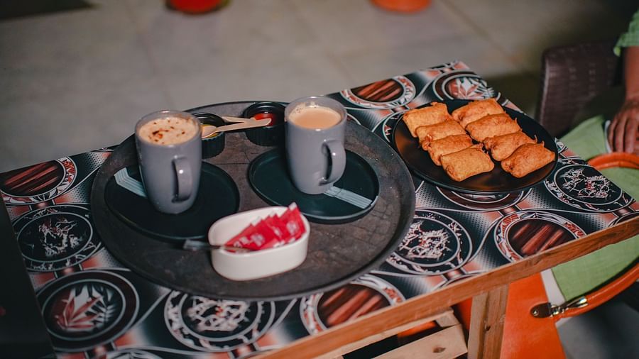 An image of a tea table where a tray is placed which has two cups of hot beverages, sauces, sugar sachets, and fritters - Rangamati Garden Resort