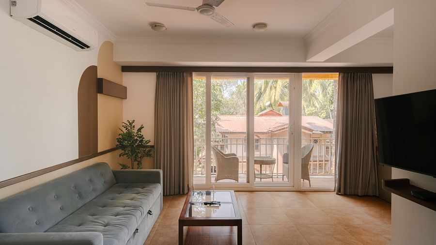 Well-lit living room with a cozy seating area and a balcony at the Two BHK apartment in Richmonde Ananta Elite, Goa.